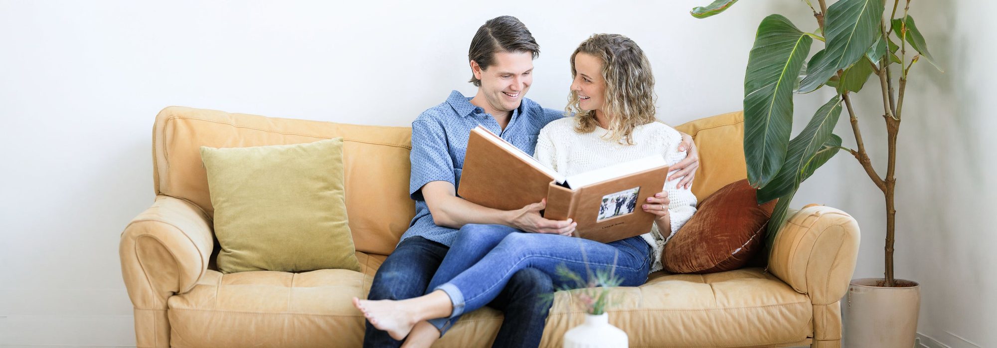 A couple on a sofa looking through a leather album with a cameo window in the cover