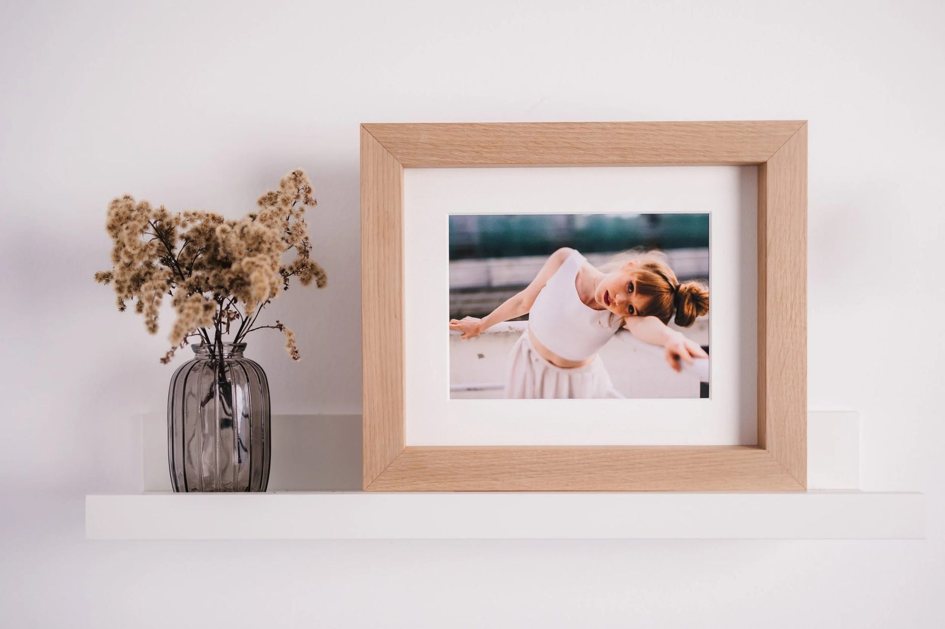 An oak frame on a pale wall, holding a portrait
